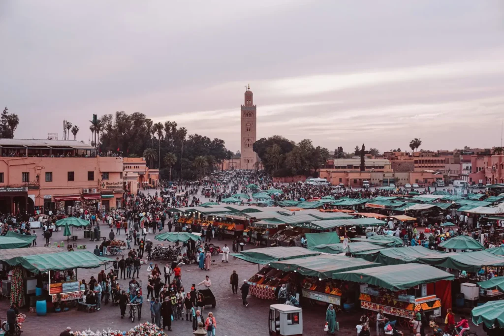 Jemaa el-Fnaa square Marrakesh Morocco with market stalls and Koutoubia Mosque at sunset.