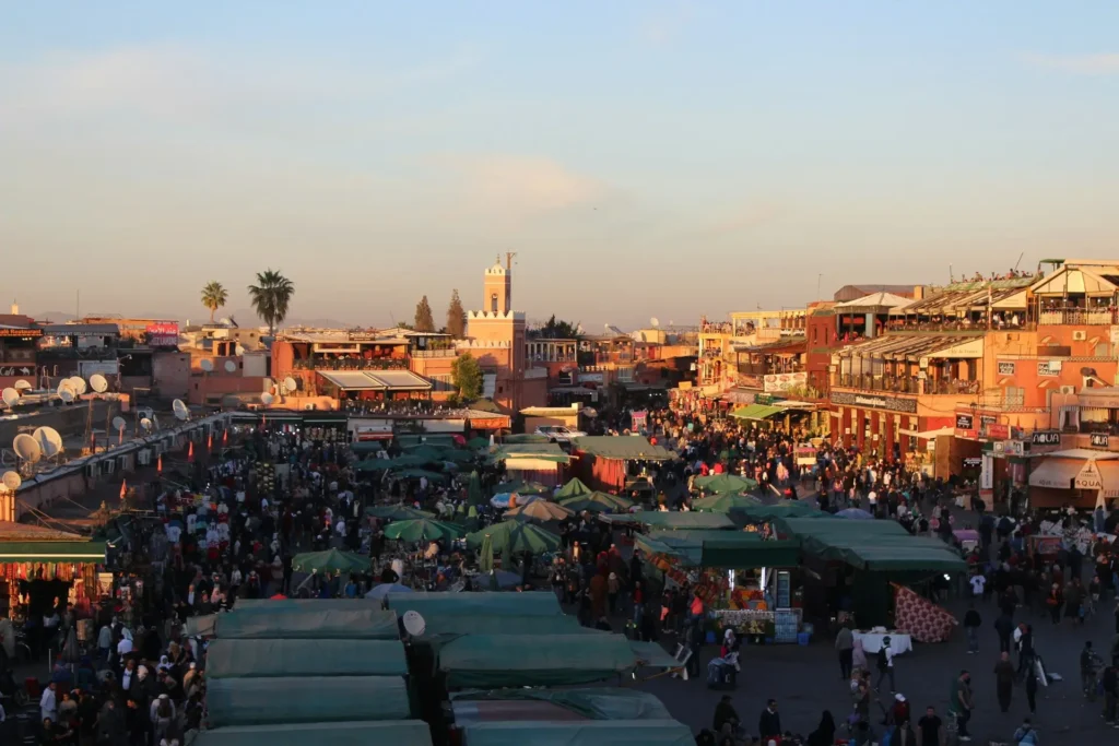 Jemaa el-Fnaa Square in Marrakech filled with market stalls, crowds, and traditional buildings at sunset