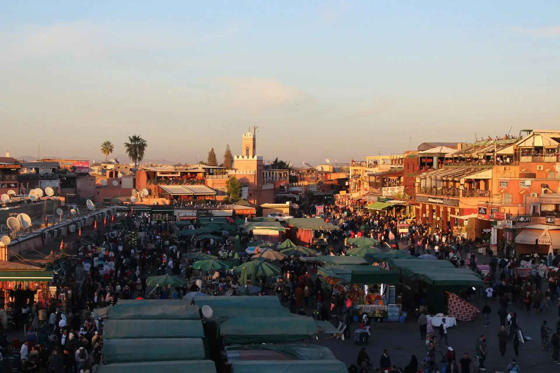 Jemaa el-Fnaa Square in Marrakech filled with market stalls, crowds, and traditional buildings at sunset