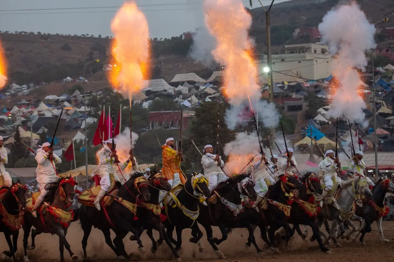Traditional Moroccan Fantasia show with riders on horseback firing rifles, celebrating Morocco’s cultural heritage.