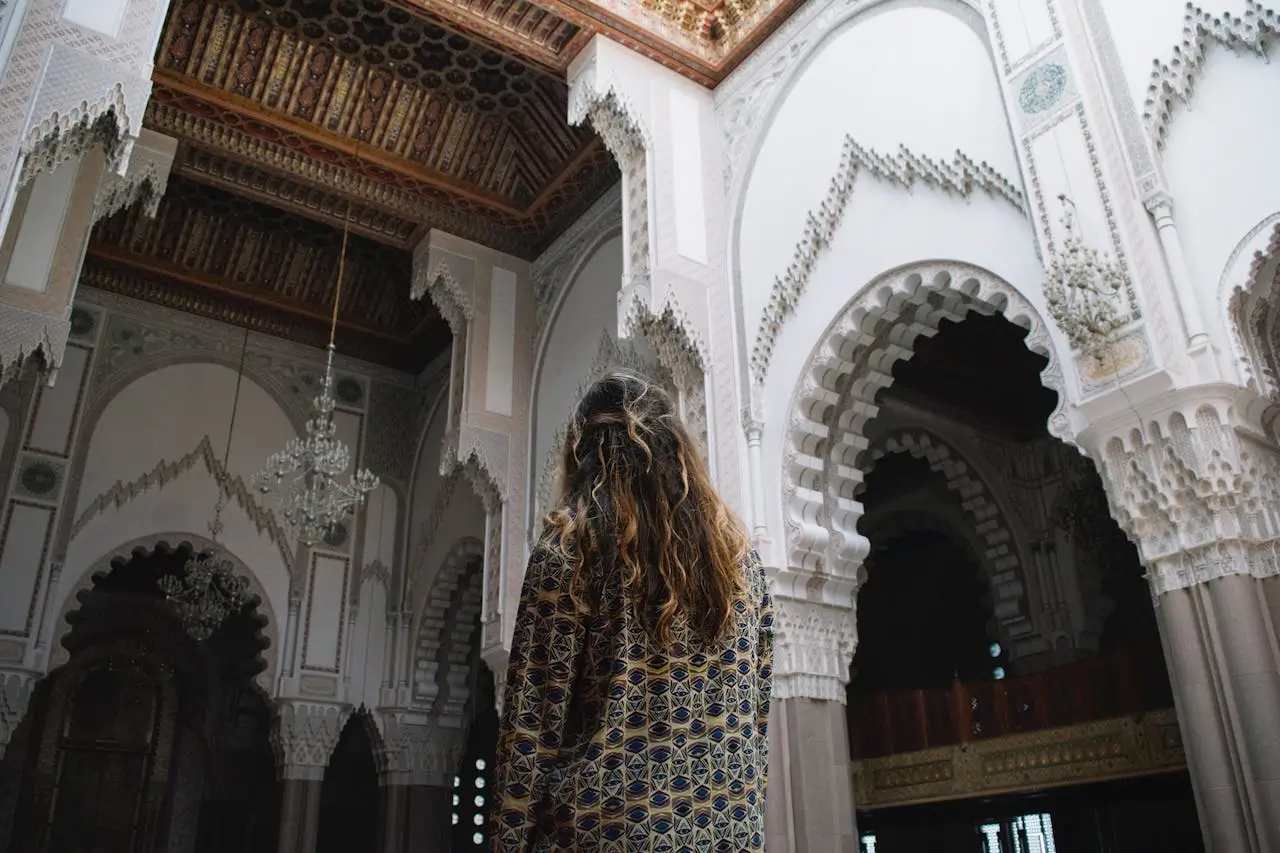 A traveler exploring the interior of a historic Moroccan mosque, showcasing Islamic architecture, arches, and traditional craftsmanship
