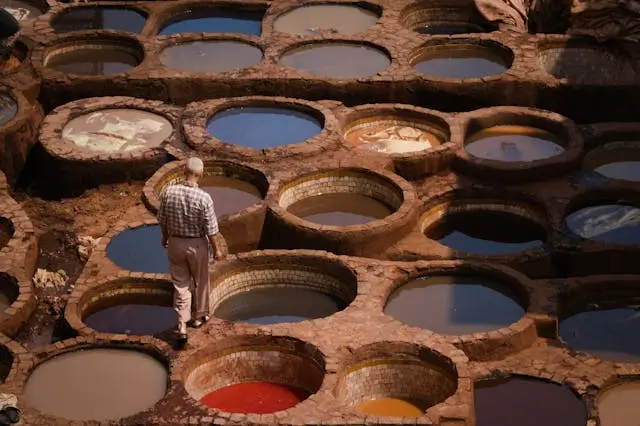 Man walking near colorful dye pits