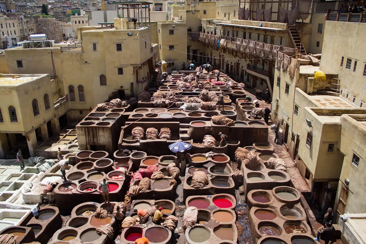 Traditional leather tanneries in Fez, Morocco, showing colorful dyeing vats and workers processing hides in the historic medina.
